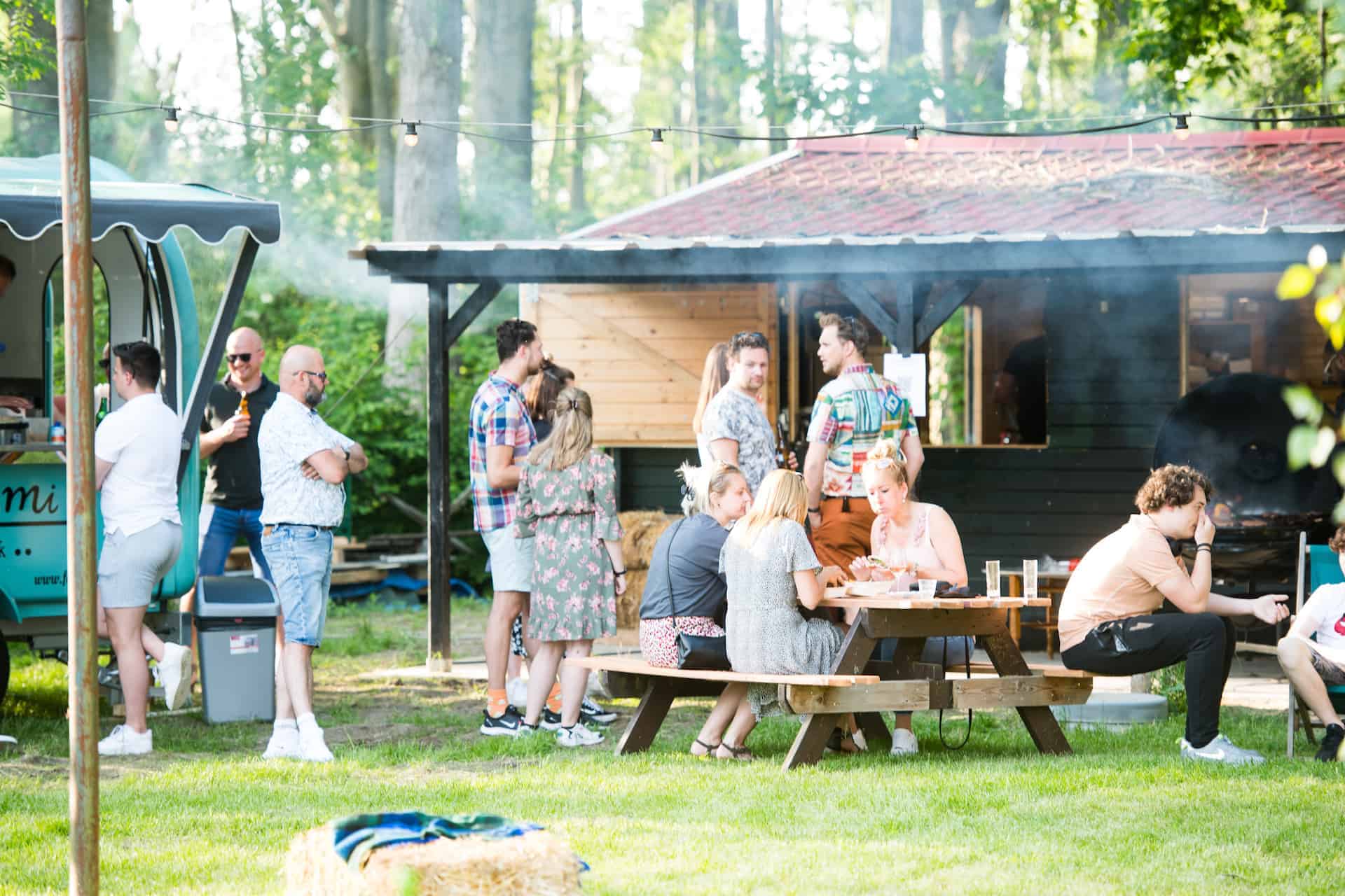 Gasten aan de picknicktafels bij de foodtruck