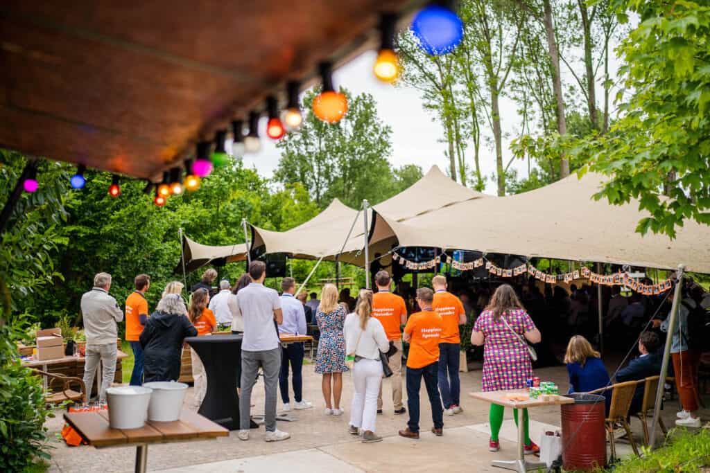 Event met kleurrijke verlichting en mensen in teamverband rondom een podium – een voorbeeld van inspirerende locaties in Nederland, verrassend centraal gelegen met voldoende zalen en directe beschikbaarheid.