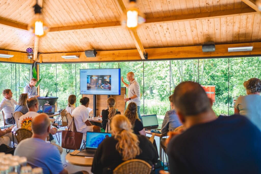 Een vergaderruimte met glazen wanden en uitzicht op het groen, waar mensen lezen, luisteren en schrijven – deze locatie biedt advies op maat, toegang tot keukenfaciliteiten en is geschikt voor elk soort evenement, van kleine bijeenkomsten tot grote bedrijven.